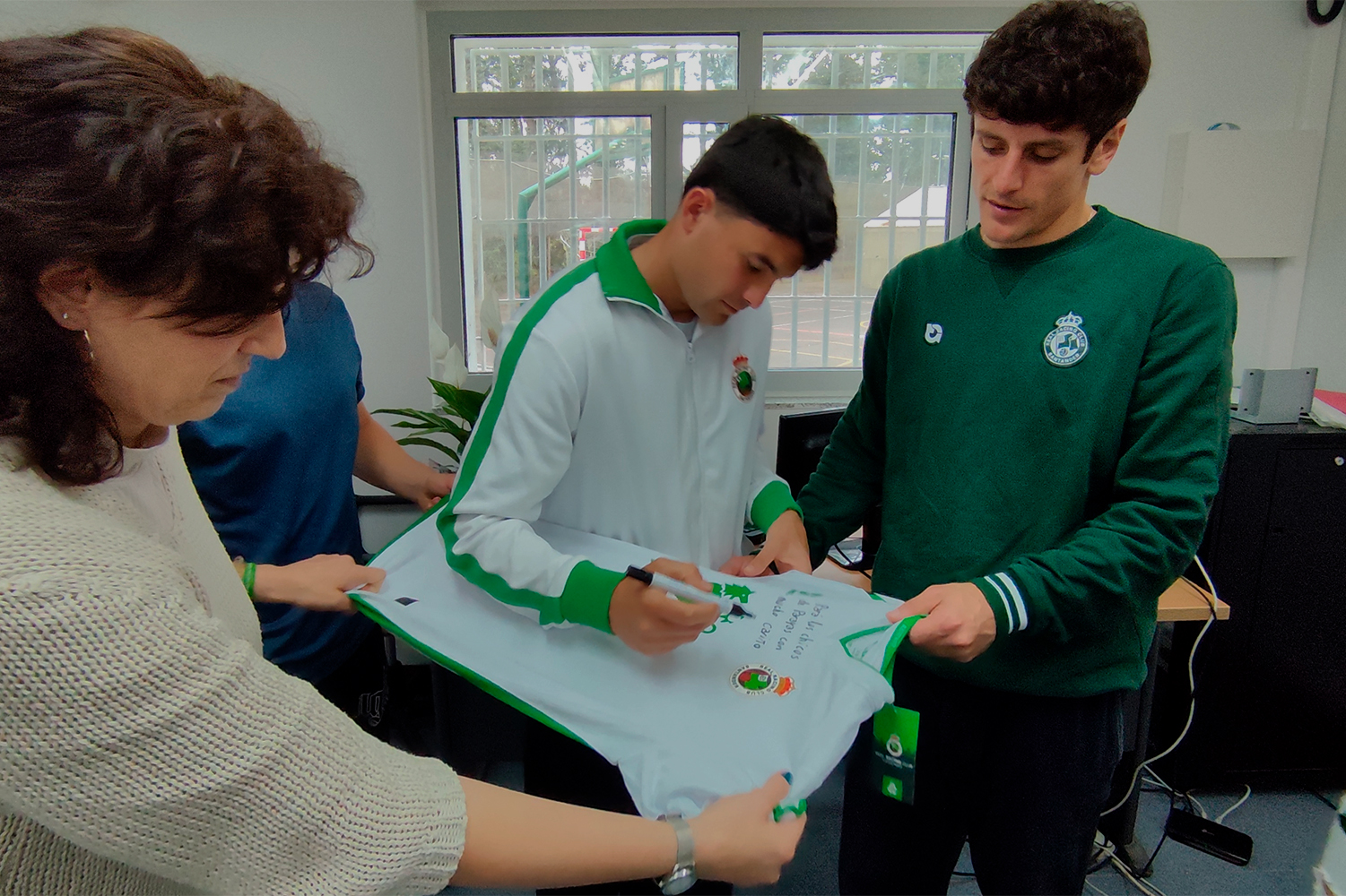 Los jugadores firman la camiseta con la que obsequiaron a las personas jóvenes