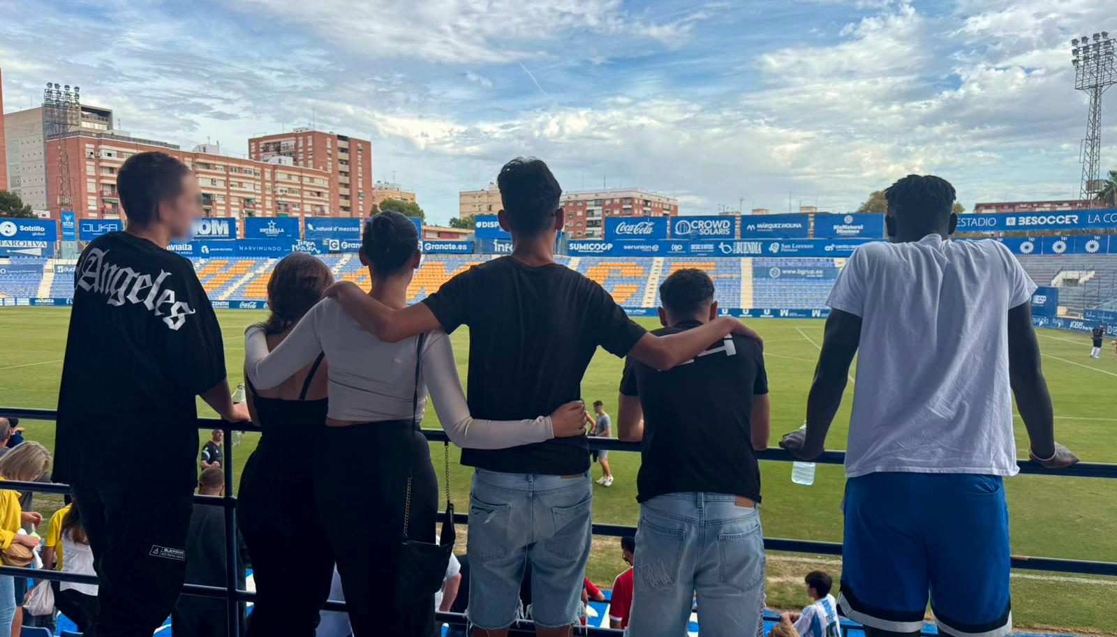 Cuatro chicos y dos chicas observan el campo desde la grada