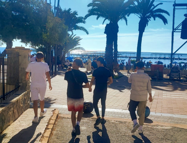 Cuatro de los jóvenes asistentes recorren el paseo de Santiago de la Ribera para asistir al espectáculo aéreo