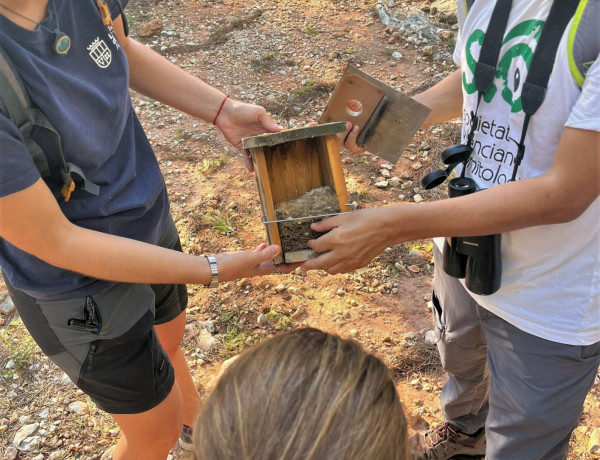 Dos profesionales del paraje muestran una de las cajas nido a una menor de la residencia