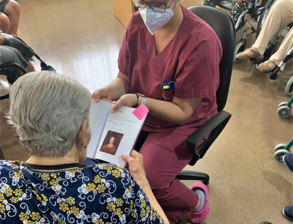 Mujer mayor leyendo un texto con ayuda de una terapeuta ocupacional