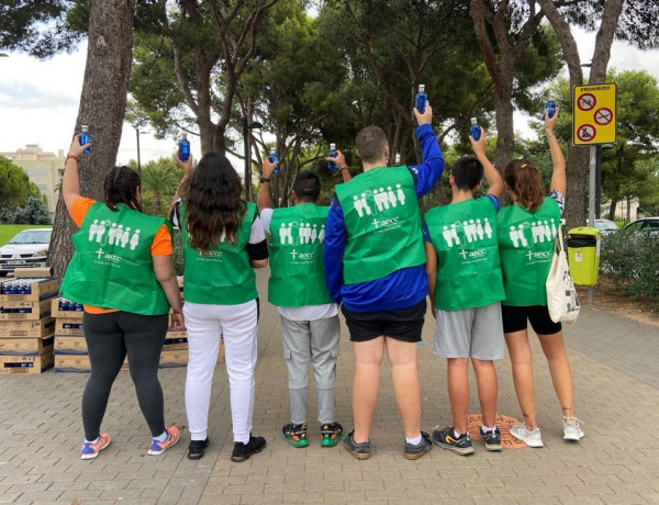 Jóvenes voluntarios en el Circuito RunCáncer 2022 levantan botellas de agua de las que reparten a los corredores