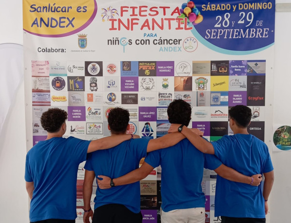 Los cuatro chicos posan junto al cartel de la fiesta