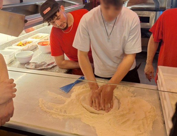 Un joven elabora la masa de la pizza