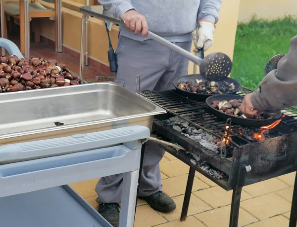 Dos profesionales de 'altavida' preparan las castañas en una barbacoa