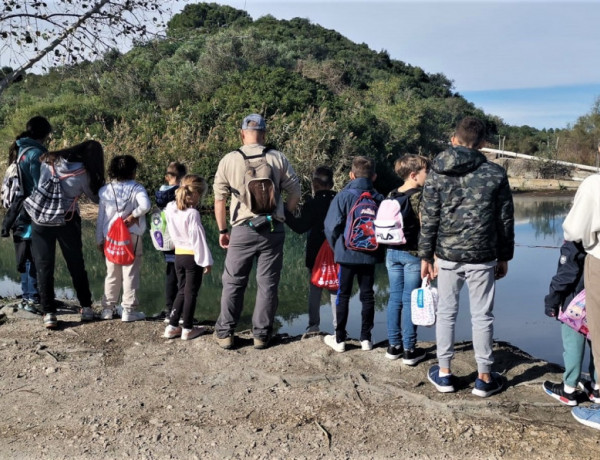 Jóvenes de 'El Palmeral', junto a otros niños y niñas frente a un lago del Parque Natural Marjal de Pego-Oliva