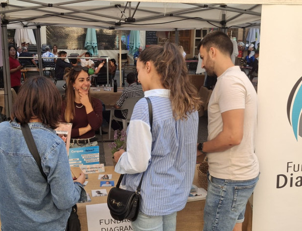 Tres personas se acercan a la mesa informativa de Fundación Diagrama