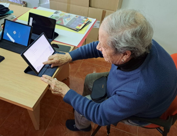 Una mujer de la residencia aprende a utilizar una tablet para buscar información por internet