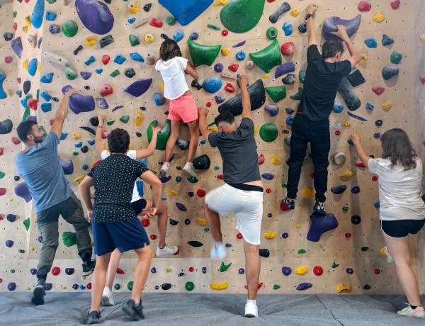 Las personas jóvenes y uno de sus educadores encaran una de las paredes del rocódromo