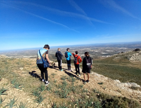 Varios jóvenes y profesionales contemplan el paisaje desde una de las cimas de la ruta