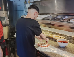 Un joven añade los ingredientes a la pizza