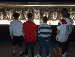 Grupo de chicos ante una vitrina con trofeos ganados por el Real Madrid CF