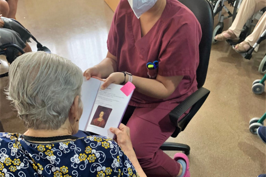 Mujer mayor leyendo un texto con ayuda de una terapeuta ocupacional