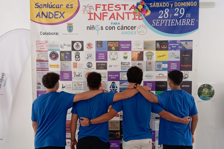 Los cuatro chicos posan junto al cartel de la fiesta