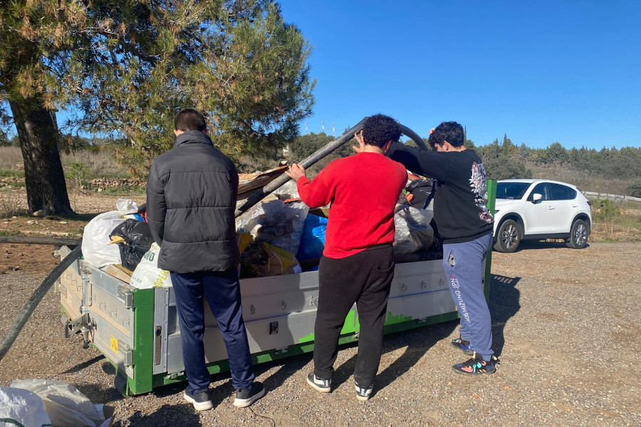 Los tres jóvenes tiran la basura recogida al contenedor habilitado