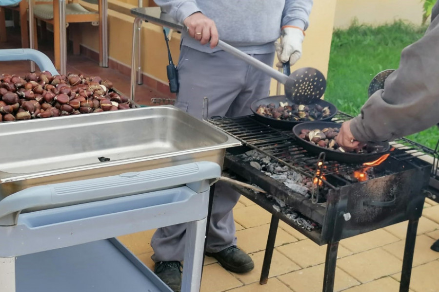 Dos profesionales de 'altavida' preparan las castañas en una barbacoa