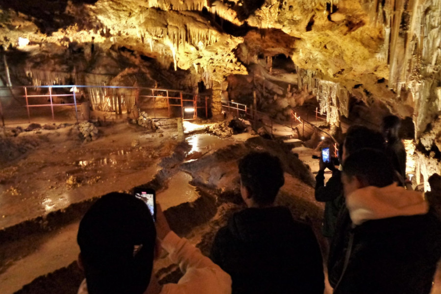 Tres jóvenes hacen fotos con sus móviles a las estalactitas en una de las cámaras de la cueva