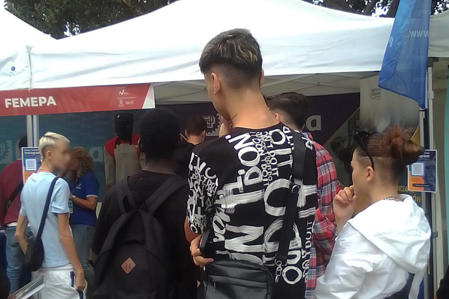 Tres jóvenes observan los puestos informativos de las empresas en la feria