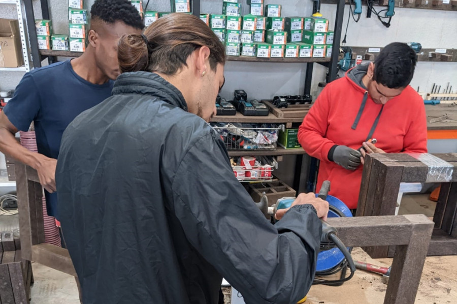 El joven de La Villa, de espaldas, aprende a fabricar una pieza de madera en el taller de la Asociación AMIF-Integrados 