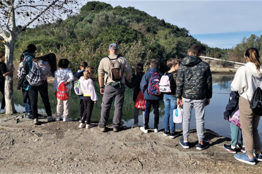 Jóvenes de 'El Palmeral', junto a otros niños y niñas frente a un lago del Parque Natural Marjal de Pego-Oliva